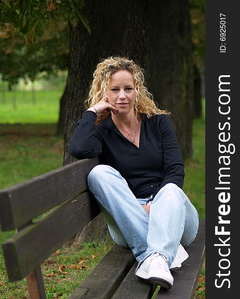 Girl sitting on bench in park. Girl sitting on bench in park