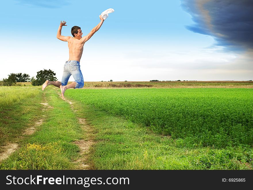 Young man jumping to meet clody skies through flat ground. Young man jumping to meet clody skies through flat ground