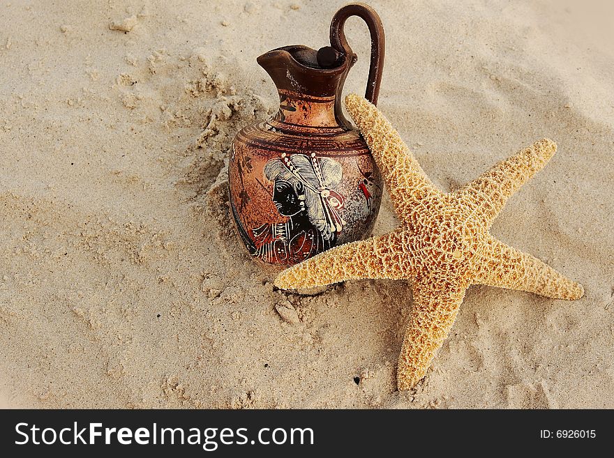Ancient jug and a starfish in yellow sand on the bank of Adriatic sea. Ancient jug and a starfish in yellow sand on the bank of Adriatic sea