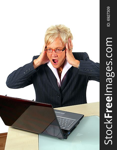 A businesswoman in her fifties in front of a laptop shocked with her hands on her head. Isolated over white. A businesswoman in her fifties in front of a laptop shocked with her hands on her head. Isolated over white.