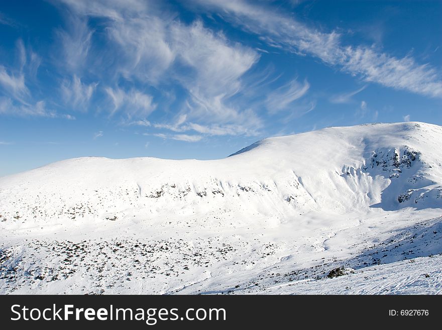 Winter sunny day over mountain slopes covered by snow