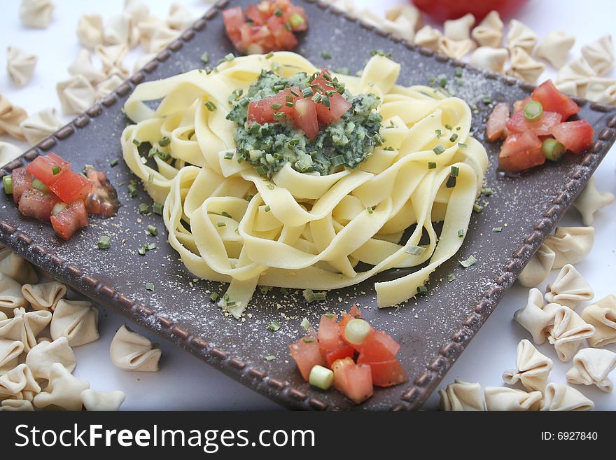A meal of italian pasta with pesto and tomatoes