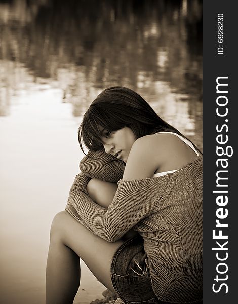 Young thoughtful woman against water background. Sepia toned.