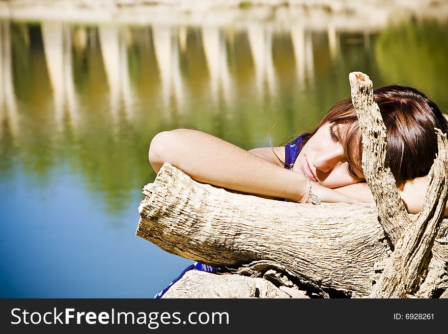 Young woman laying over old tree trunk. Young woman laying over old tree trunk.