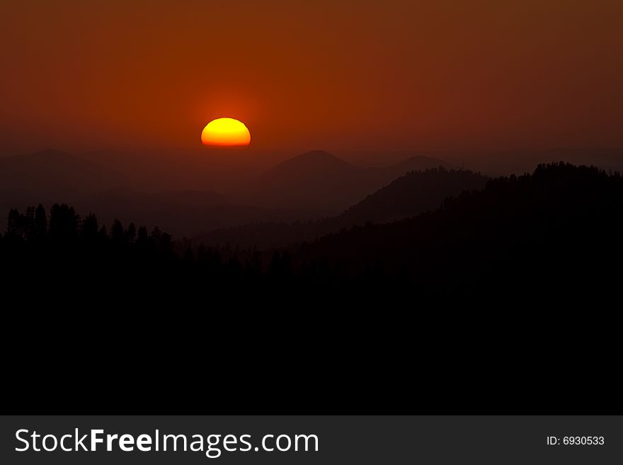 The sun sets behind layers of mountains in the Sierra Mountains of California. The sun sets behind layers of mountains in the Sierra Mountains of California.