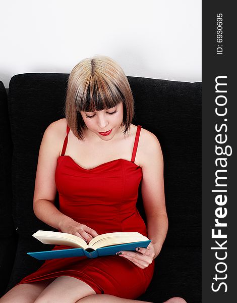 Beautiful blond girl in red dress reading a book