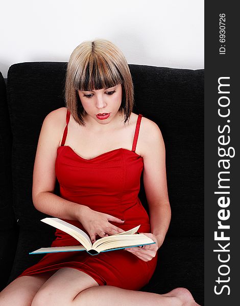 Beautiful blond girl in red dress reading a book