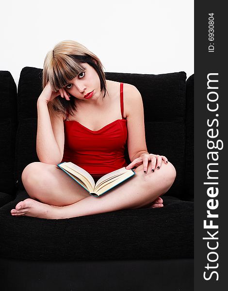 Beautiful blond girl in red dress reading a book with sad and bored expression