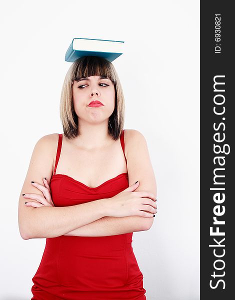 Beautiful blond girl with a book on his head and sad expression