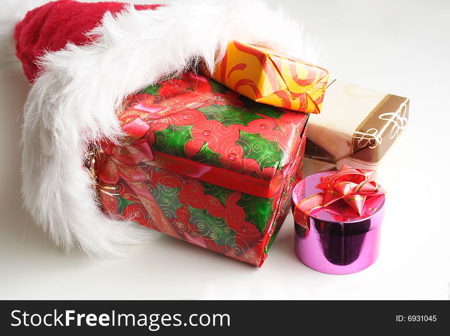 Santa's red hat and small gifts in white background. Santa's red hat and small gifts in white background