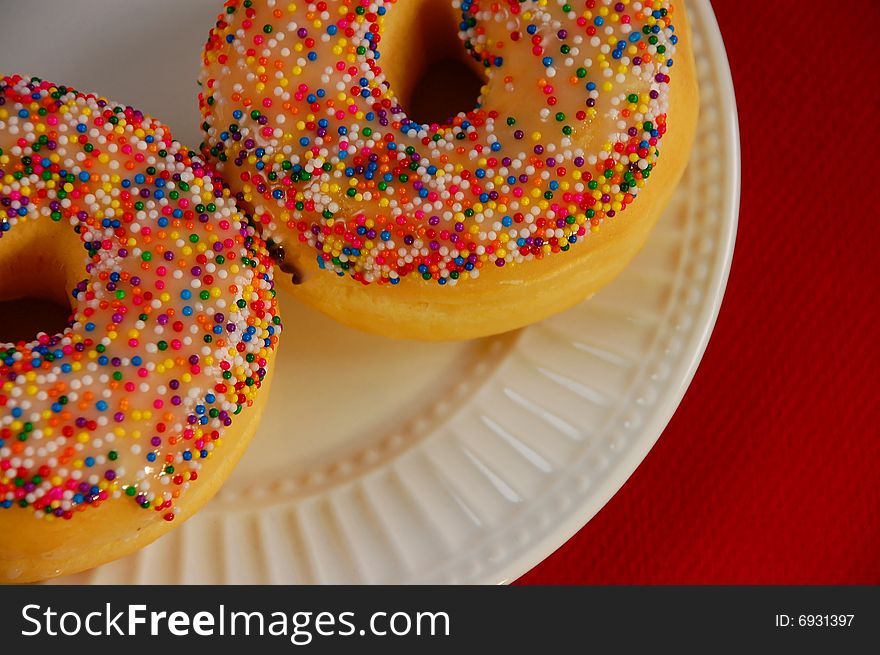 Sprinkle donuts on white plate against white background