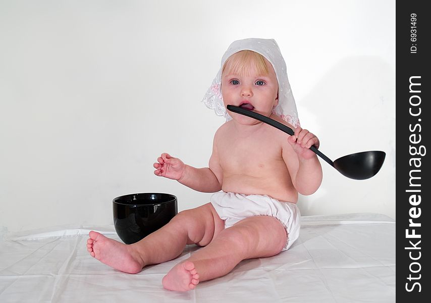 Child in hat plays ladle. Child in hat plays ladle
