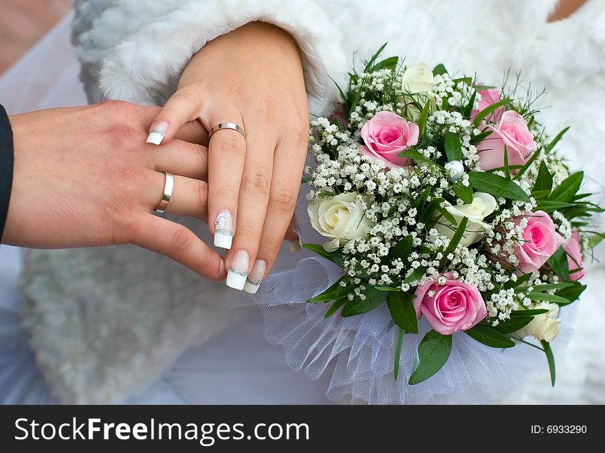 Newly-weds hold a wedding bouquet in the hands