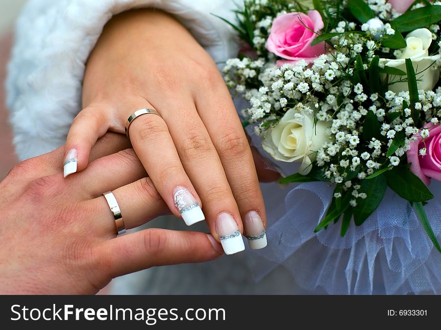 Newly-weds hold a wedding bouquet in the hands