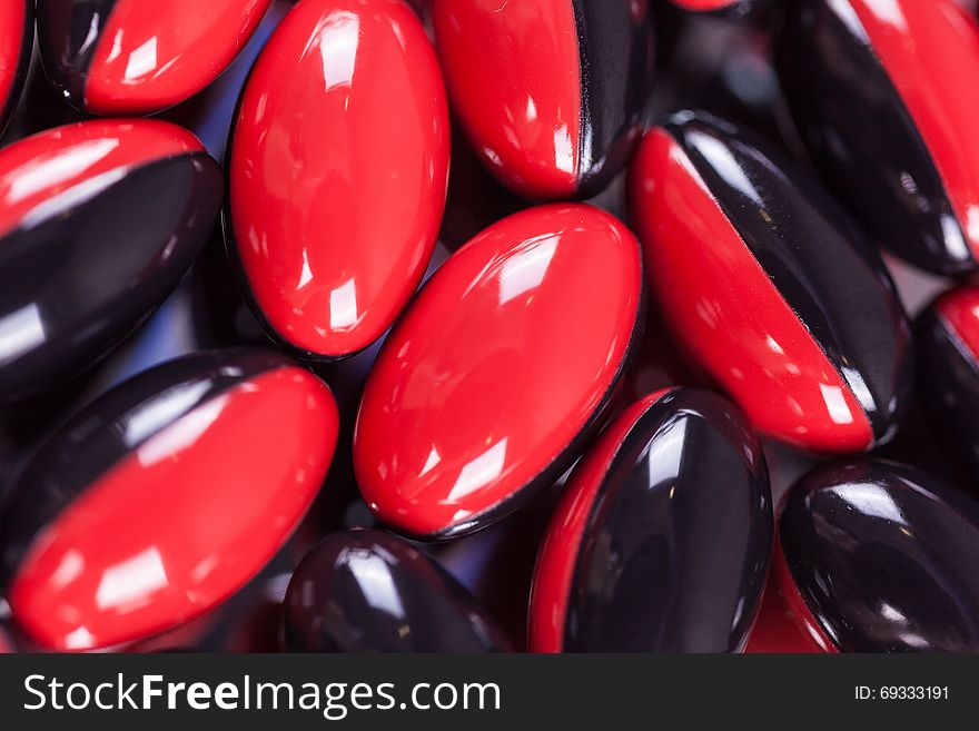 A scattering of red-black brown pills on the mirror background, macro, picture with depth of field