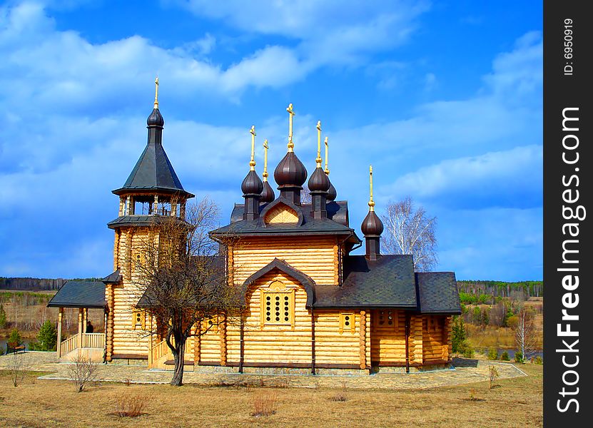 Rural orthodox church from logs on a background of the blue sky and clouds. Rural orthodox church from logs on a background of the blue sky and clouds