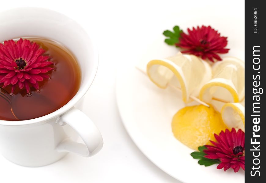 Cup of tea near the plate with lemon and flowers. Cup of tea near the plate with lemon and flowers