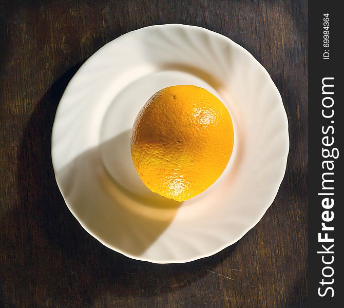 Ripe orange in white plate on wooden background