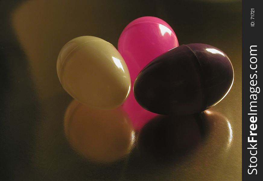 Colorful plastic Easter eggs, with a single light source from the side, on a metallic gold background. A modern, abstract sort of Easter image. Colorful plastic Easter eggs, with a single light source from the side, on a metallic gold background. A modern, abstract sort of Easter image.