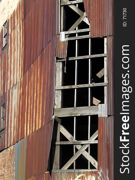 Section of an old warehouse with rusty corrugated siding and gaping, broken windows. Section of an old warehouse with rusty corrugated siding and gaping, broken windows.