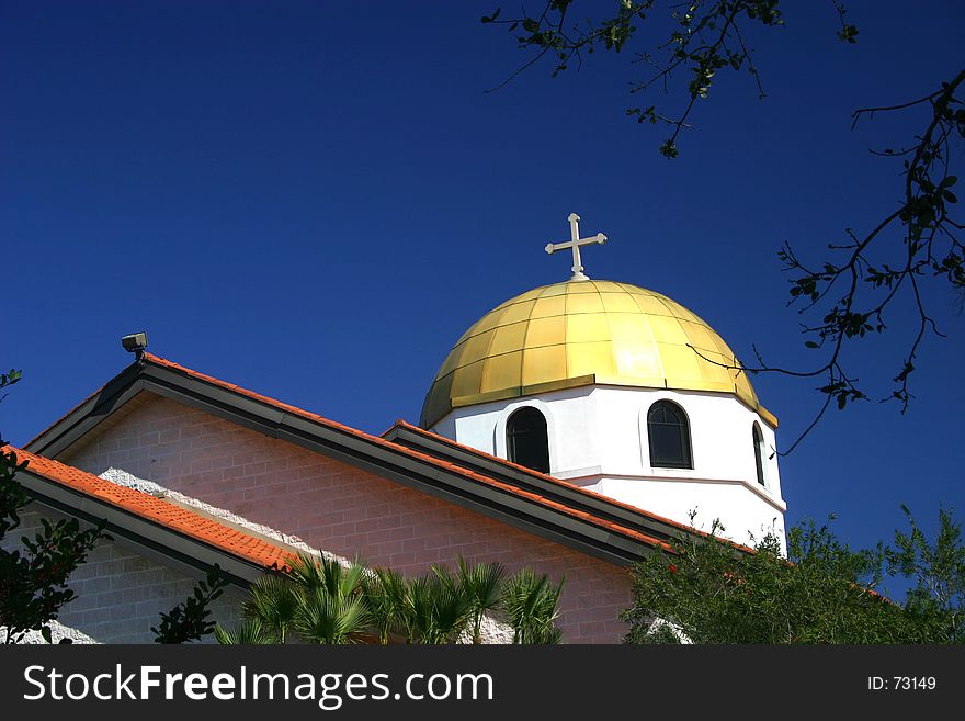 Gold dome and cross of Greek church against a blue sky