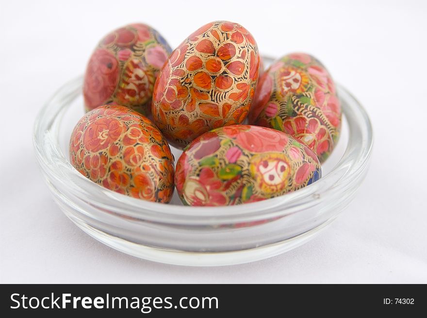 A glass dish full of red decorative eggs. A glass dish full of red decorative eggs