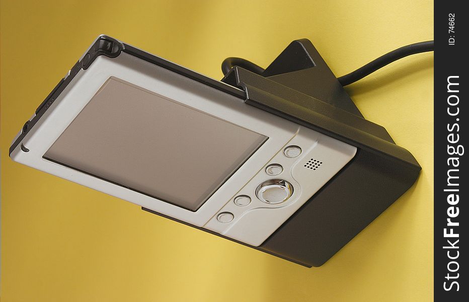 Pocket pc in charger against a yellow background