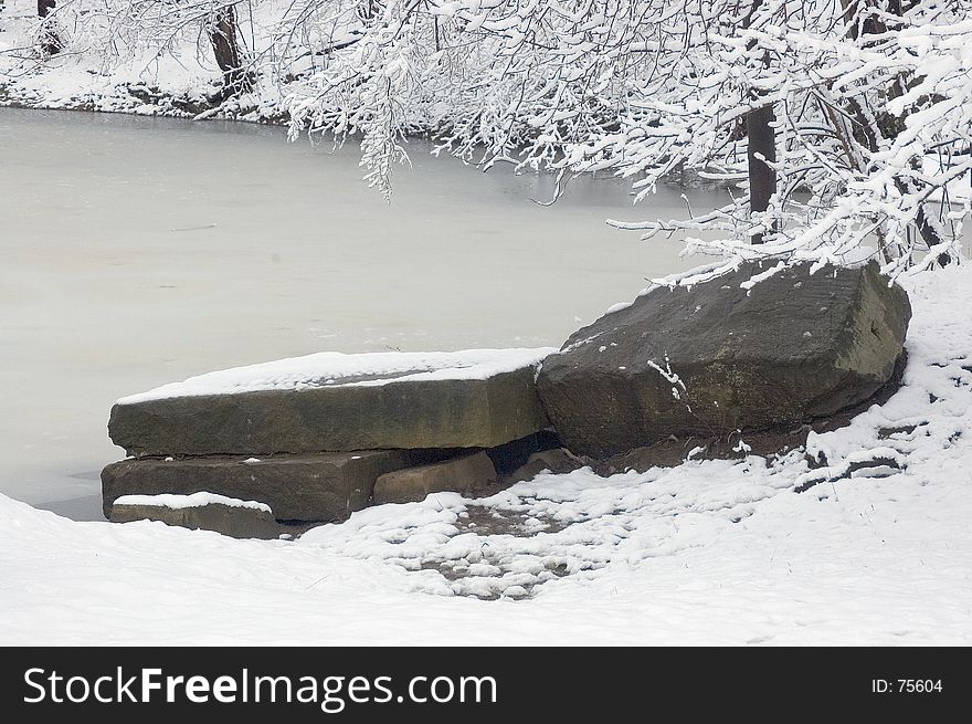 3 large rocks from a quarry at the lakes edge form a natural dock. Photograph taken in mid winter after a light snow storm. Lake is frozen over. 3 large rocks from a quarry at the lakes edge form a natural dock. Photograph taken in mid winter after a light snow storm. Lake is frozen over