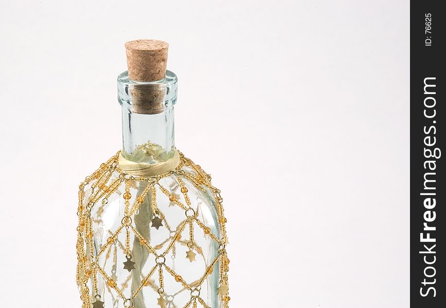 A corked, clear bottle with an ornamental dressing draped over it. A corked, clear bottle with an ornamental dressing draped over it.