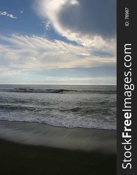 Rolling waves on the beach while whispy clouds dance above. Rolling waves on the beach while whispy clouds dance above