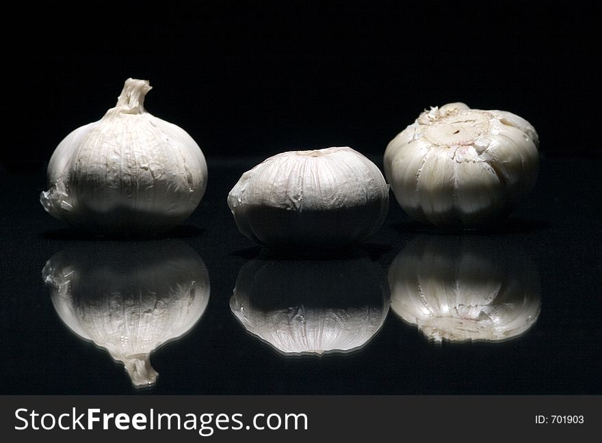 Three fresh white garlics with reflex sprinkled with water