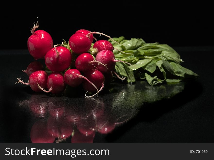 Fresh red radish spinkled with water on a glass surface