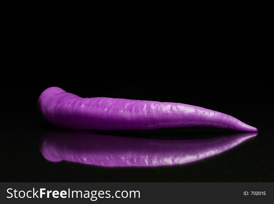 Violet paprika with reflex on black background