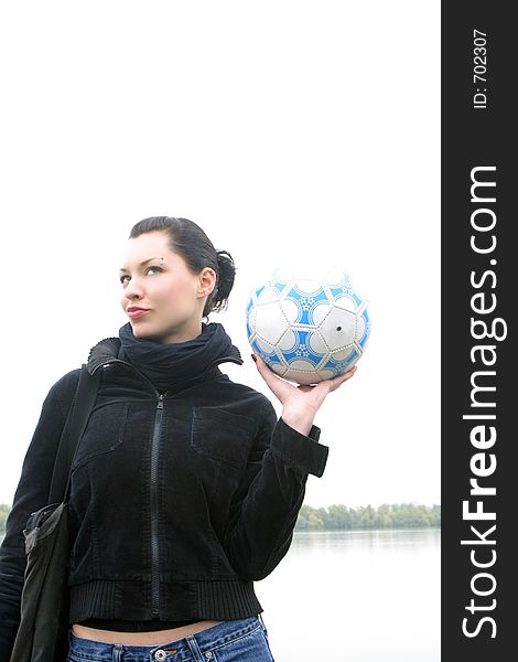 Girl holding in the hand ball with river and sky in background. Girl holding in the hand ball with river and sky in background