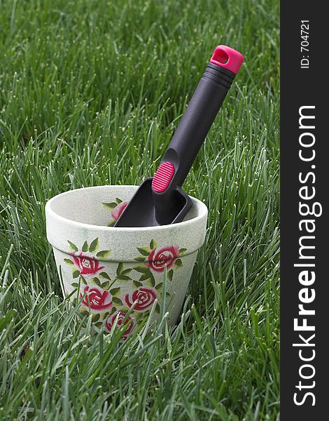 Hand shovel tool and flower pot on a grass background. Hand shovel tool and flower pot on a grass background