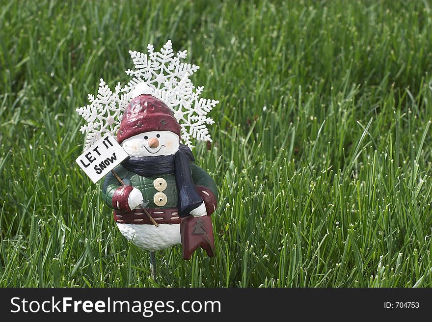 Let it snow figure on green grass with room for logo,caption,text,. Let it snow figure on green grass with room for logo,caption,text,