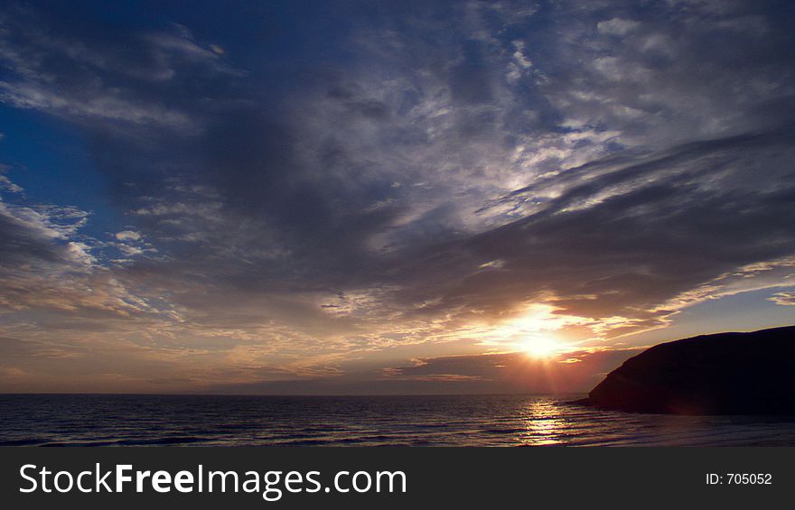 Sunset over St Bees Head in Cumbria, UK. Wide big sky with swept cloud patterns. Sunset over St Bees Head in Cumbria, UK. Wide big sky with swept cloud patterns.