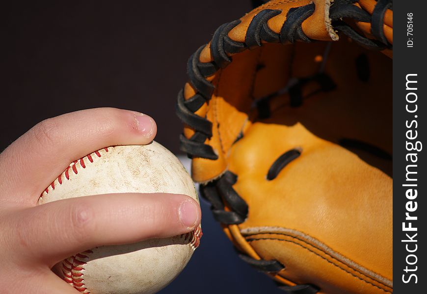A hand holds a baseball and a leather catcher's glove. A hand holds a baseball and a leather catcher's glove
