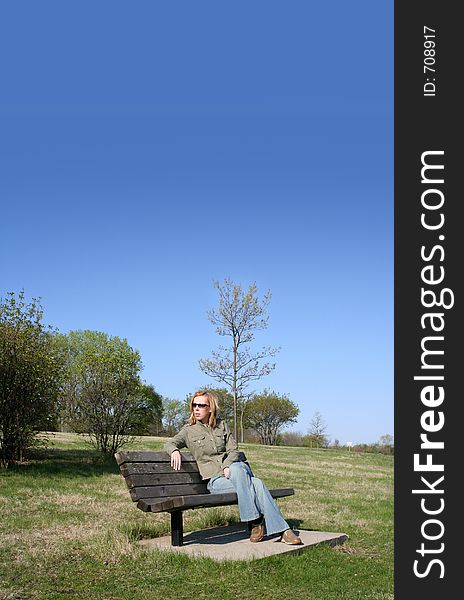 A girl sitting on the bench in the park.