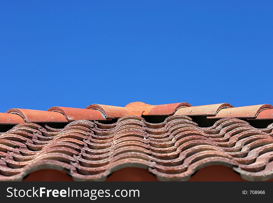 Orange roof tiles radiate from a point with blue sky above. Orange roof tiles radiate from a point with blue sky above