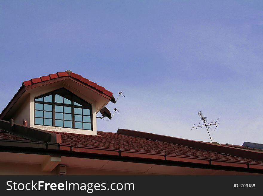 Roof of a house, skylight and television antenna against the sky