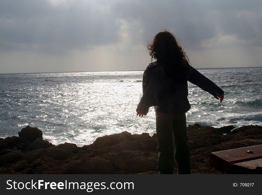 Young girl by the rocky coast after the rain. Young girl by the rocky coast after the rain