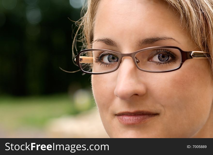 Closeup of young woman with glasses on the nature background