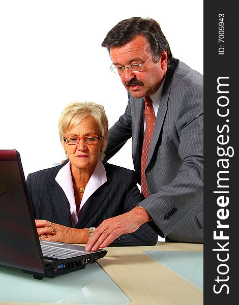 A business woman and a man in front of a laptop on a desk. The man explains something to the woman. Isolated over white. A business woman and a man in front of a laptop on a desk. The man explains something to the woman. Isolated over white.