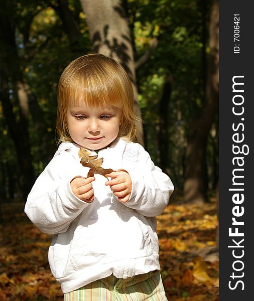 Autumn portrait of cute little girl with oak leaf