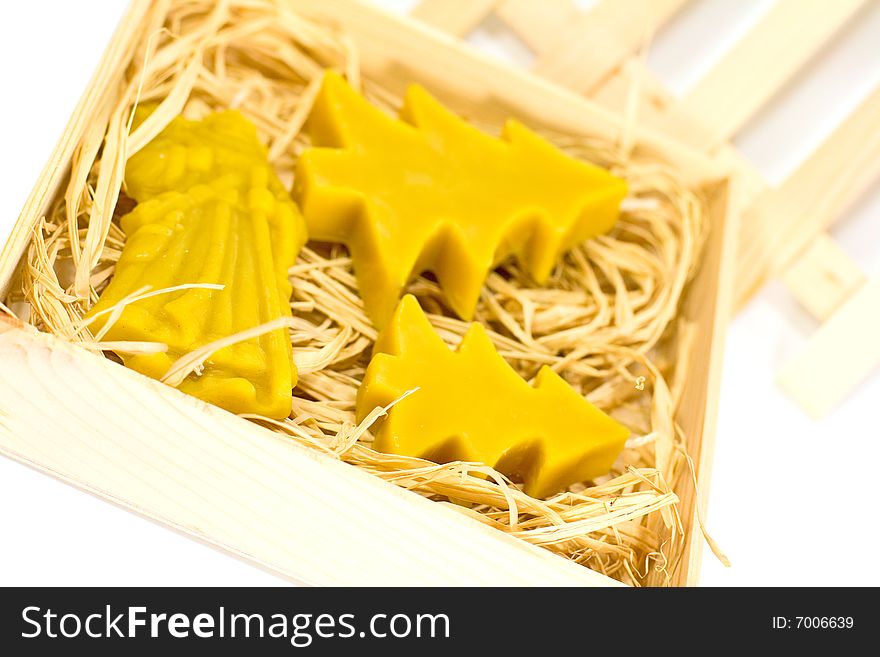 Closeup of handmade yellow christmas candles in the wooden box with straw