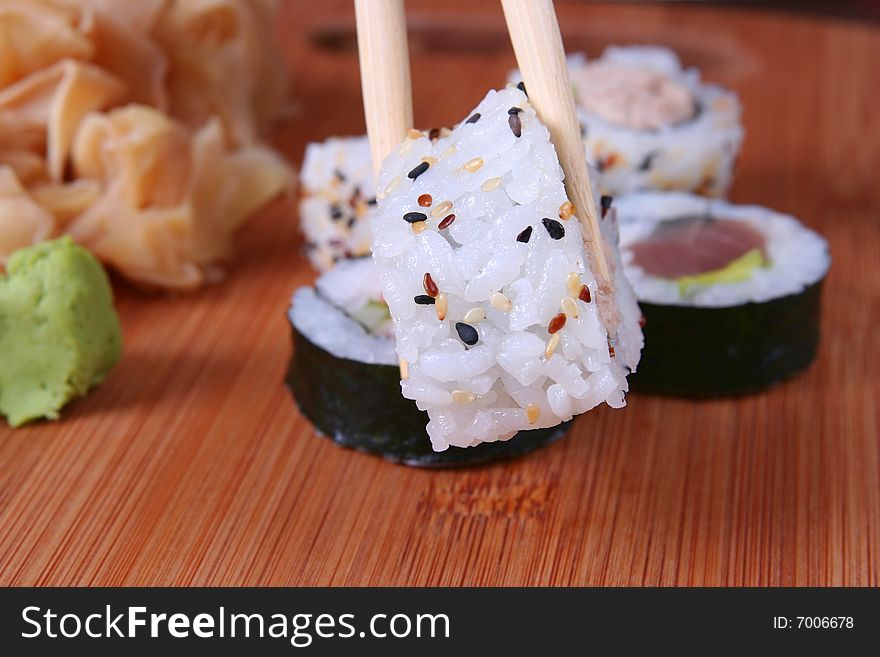 Appetizer sushi with chopsticks on wooden desk
