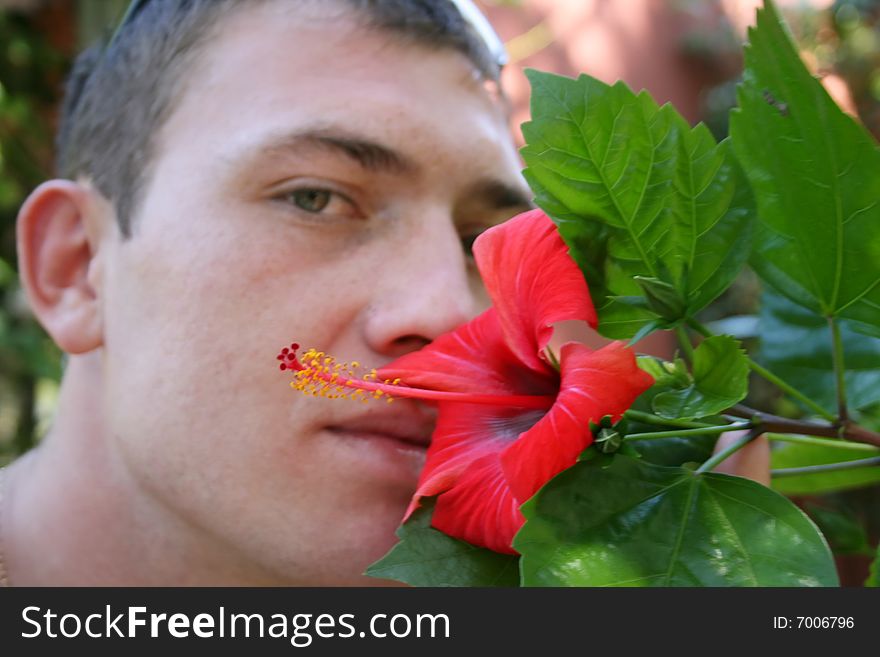 The man smells a red exotic flower. The man smells a red exotic flower