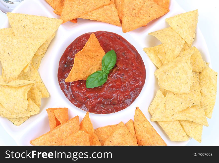 Nachos and salsa dip with basil , in a bowl