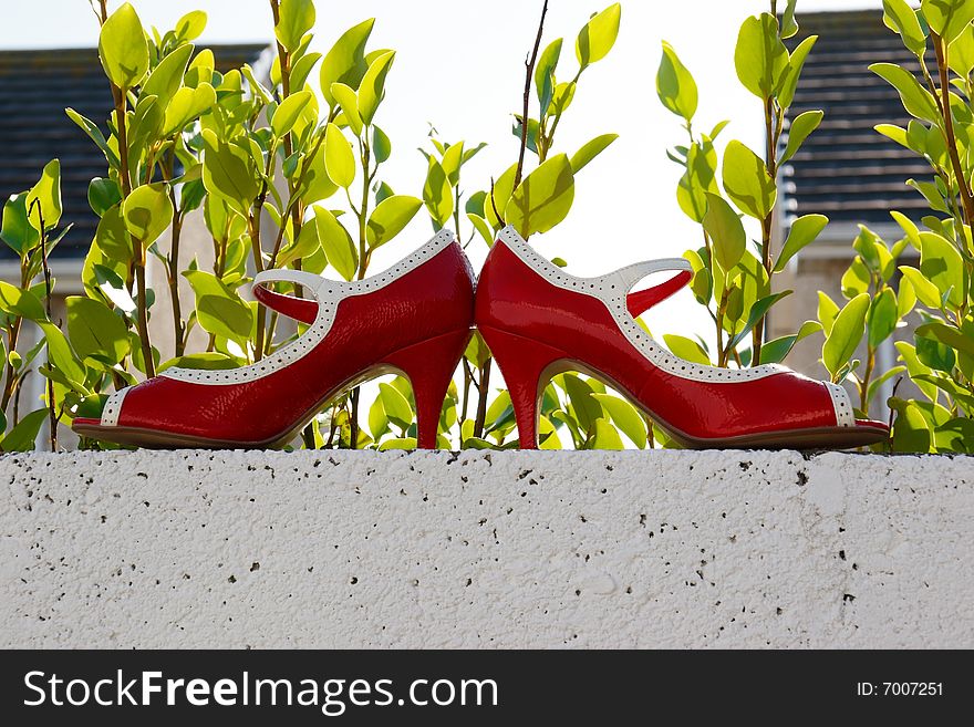 Red high heels on a white wall with council estate background. Red high heels on a white wall with council estate background